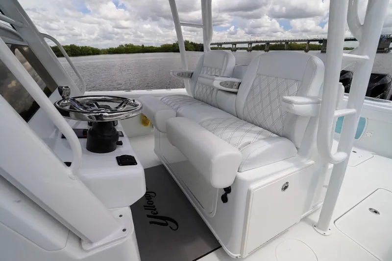 Slide: The Image of 2020 Yellowfin 39 Offshore boat interior with white seating and steering wheel, on a calm river. - 24