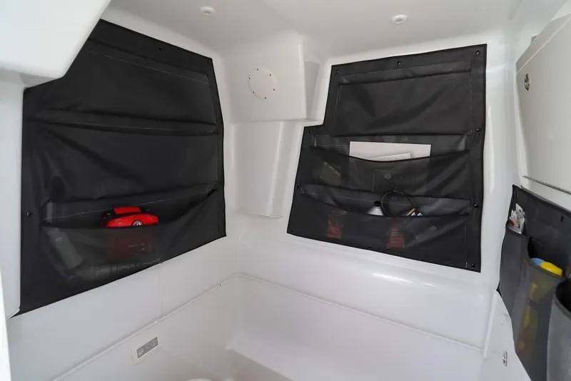 Slide: The Image of 2020 Yellowfin 39 Offshore cabin storage with black mesh pockets and white interior. - 43