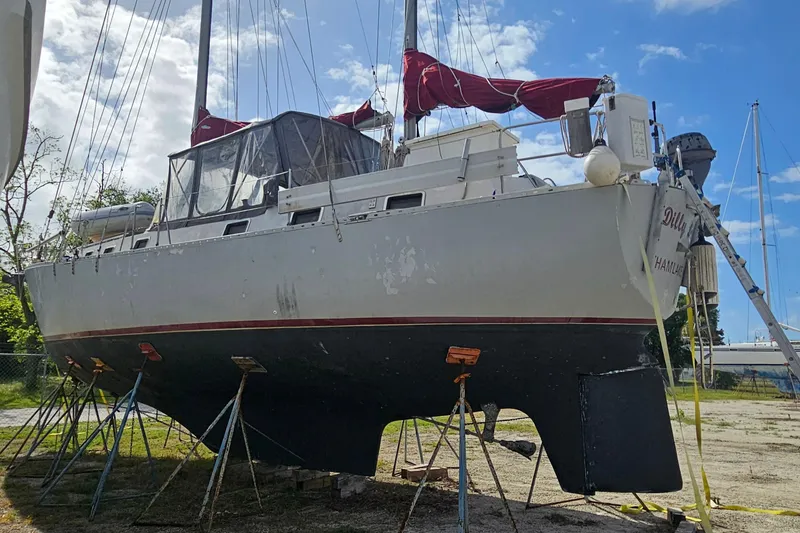 Slide: The Image of 1982 Morgan 462 sailboat on stands, with red sails and clear sky background. - 10
