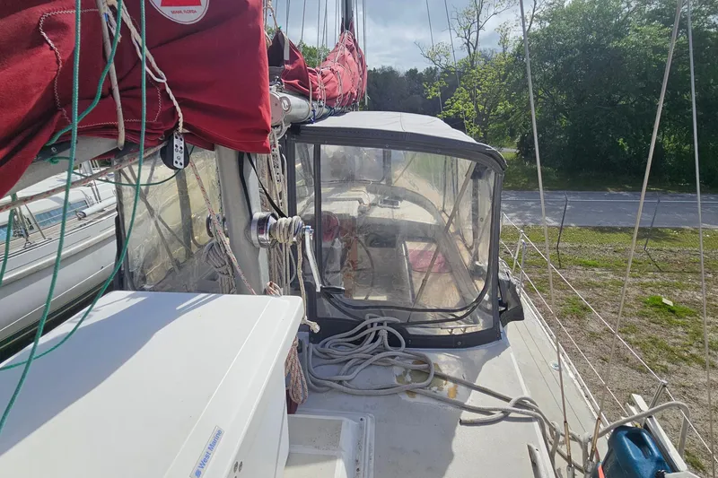 Slide: The Image of 1982 Morgan 462 sailboat deck with red sails and rigging, docked near greenery. - 14