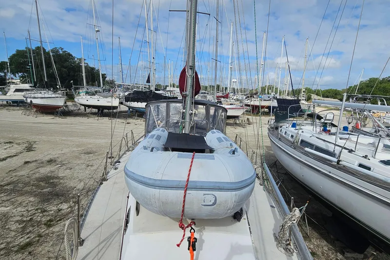 Slide: The Image of 1982 Morgan 462 sailboat with dinghy on deck, surrounded by other boats in a marina. - 17