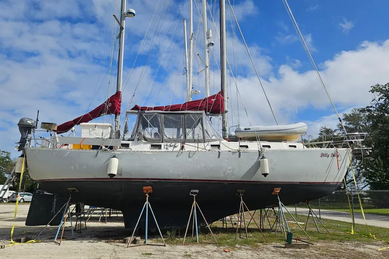Slide: The Image of 1982 Morgan 462 sailboat on stands, with red covers, under a blue sky. - 2