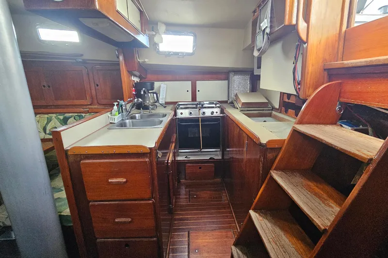 Slide: The Image of 1982 Morgan 462 yacht interior with wooden cabinetry, compact kitchen, and stairs. - 29