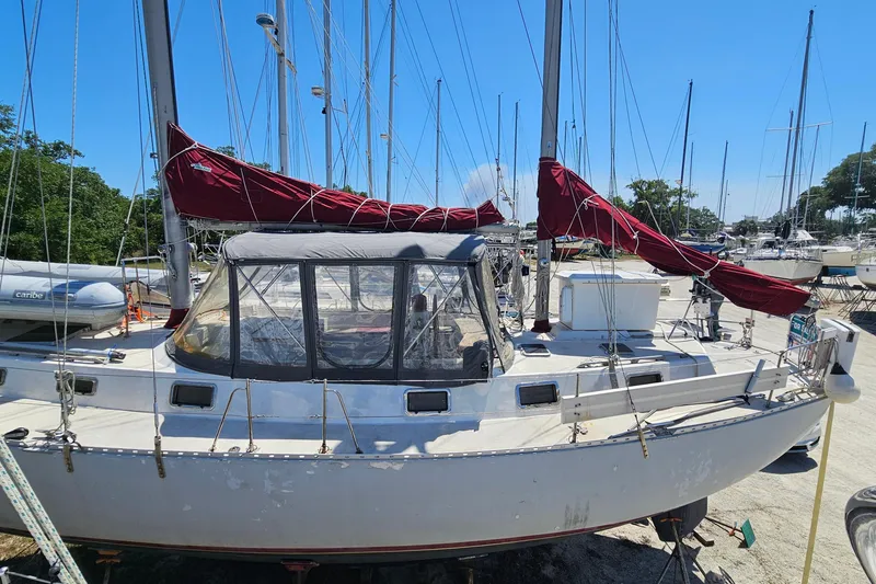 Slide: The Image of 1980 Morgan 462 sailboat with red sails docked at a marina under clear blue skies. - 65