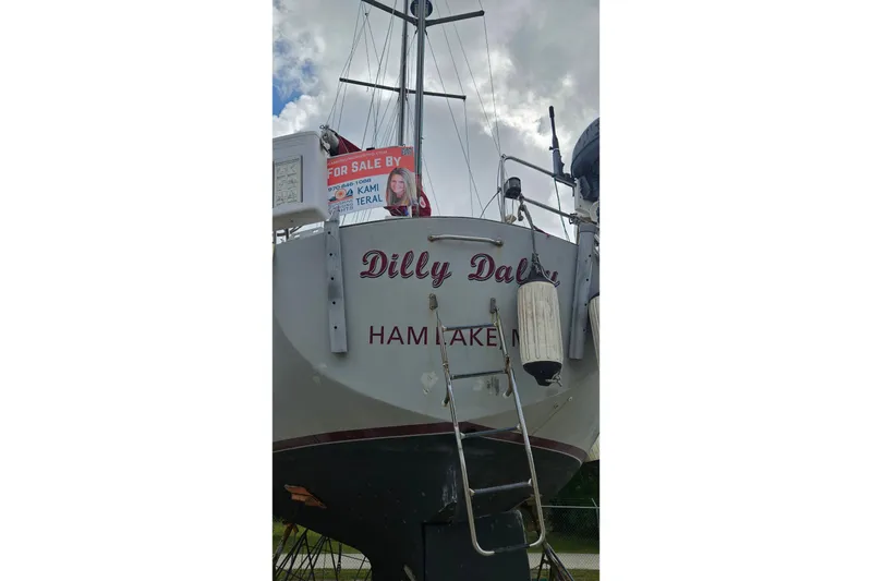 Slide: The Image of 1980 Morgan 462 sailboat docked, featuring red sails and a covered cockpit area. - 68