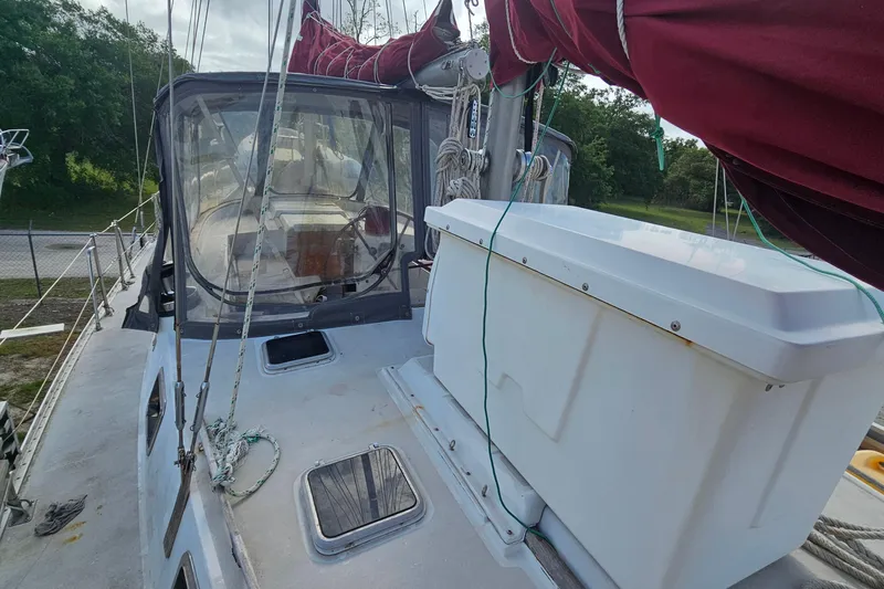 Slide: The Image of 1982 Morgan 462 sailboat deck with ropes, storage box, and canopy, docked near greenery. - 15