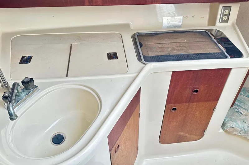 Slide: The Image of 1996 Hunter Marine 280 yacht kitchen with sink, stove, and wooden cabinets. - 7