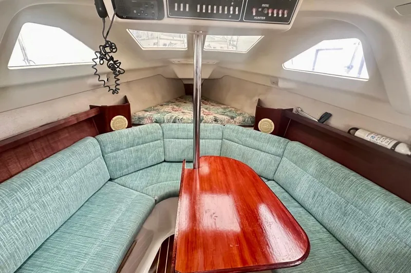 Slide: The Image of Interior of a 1996 Hunter Marine 280 sailboat with teal seating and wooden table. - 8