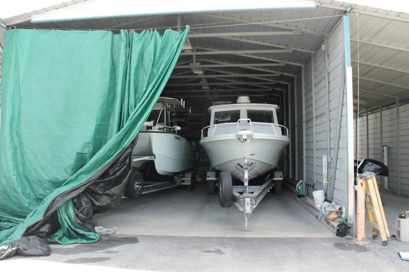 Slide: The Image of 2015 Stamas Americana 26 boat stored in a covered garage with green curtain. - 2