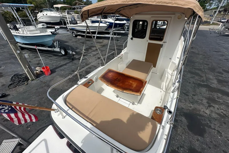 Slide: The Image of 2015 Ranger Tugs R-21 EC boat with tan canopy and seating, docked at a marina. - 10