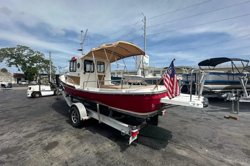 Slide: The Image of 2015 Ranger Tugs R-21 EC boat on trailer with American flag, parked outdoors. - 2
