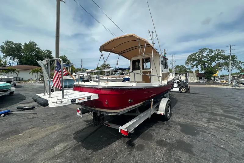 Slide: The Image of 2015 Ranger Tugs R-21 EC boat on trailer, featuring red hull and American flag. - 4