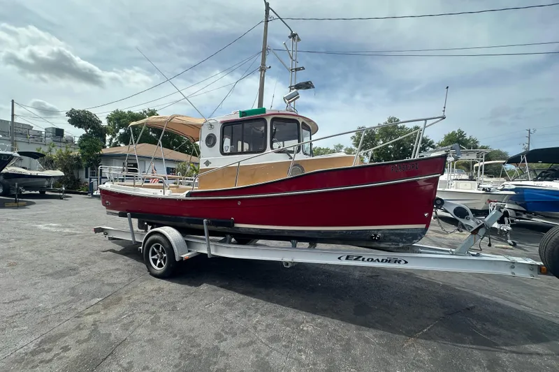 Slide: The Image of 2015 Ranger Tugs R-21 EC boat on trailer, red hull, parked outdoors. - 5