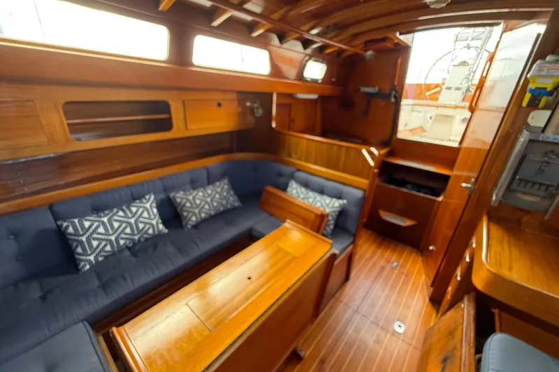 Slide: The Image of Interior of 1986 Vindo 45 sailboat with wooden finish and blue cushioned seating. - 12