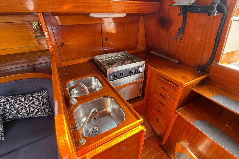 Slide: The Image of 1986 Vindo 45 yacht kitchen with dual sinks, stove, and wooden cabinetry. - 26