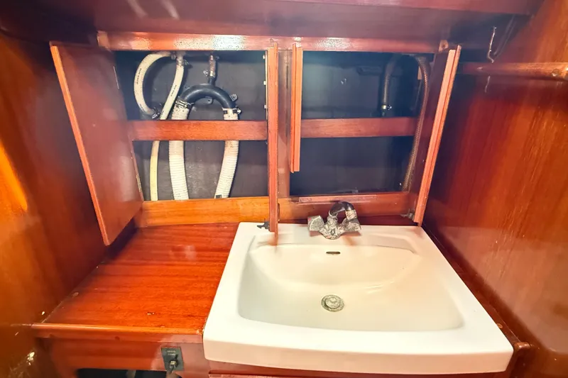 Slide: The Image of Wooden cabinet with open doors above a white sink in a 1986 Vindo 45 boat. - 44