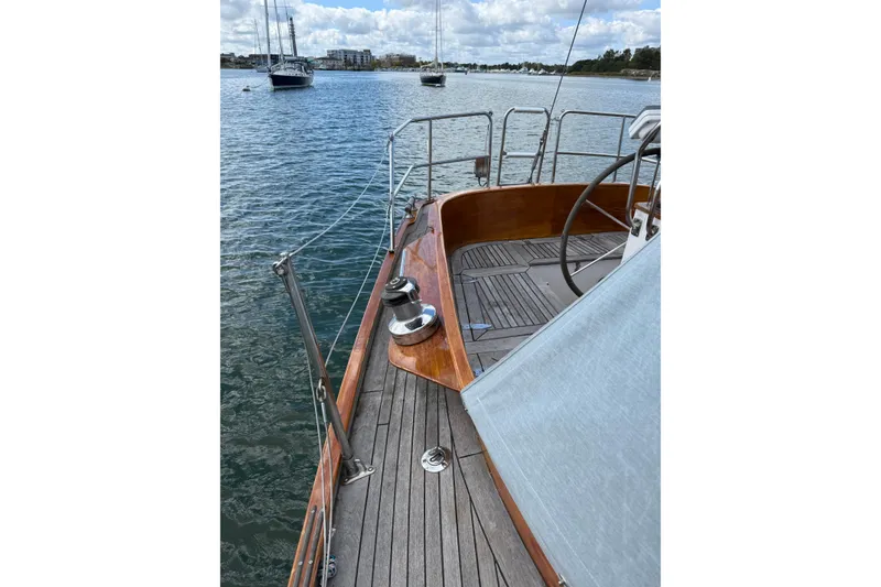 Slide: The Image of Sailboat deck view of 1986 Vindo 45, featuring wooden details and scenic harbor. - 50