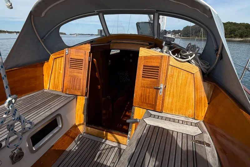 Slide: The Image of 1986 Vindo 45 sailboat cockpit with wooden doors and deck, moored on a calm lake. - 51