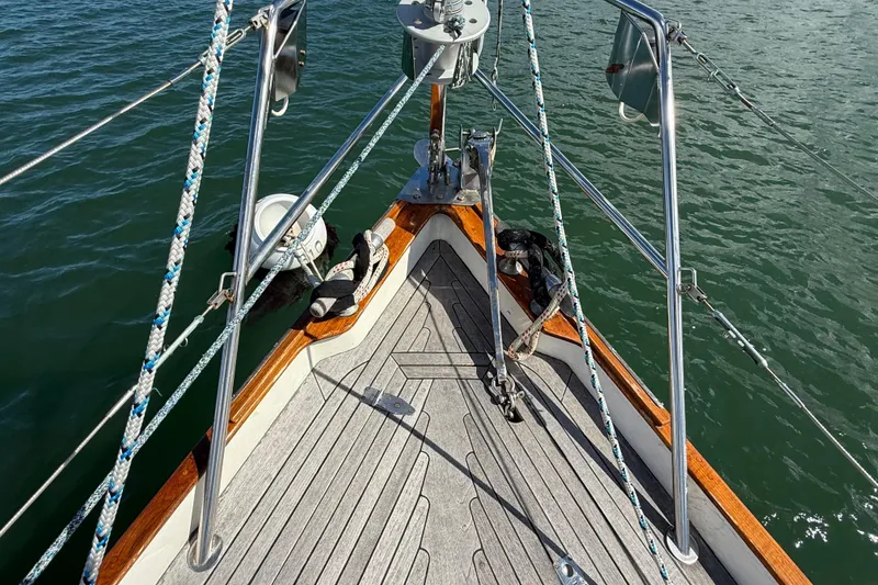 Slide: The Image of Bow of 1986 Vindo 45 sailboat with ropes and anchor, on calm water. - 60