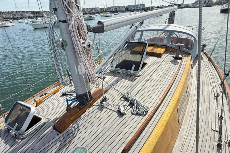Slide: The Image of 1986 Vindo 45 sailboat deck with ropes and hatches in a marina setting. - 66