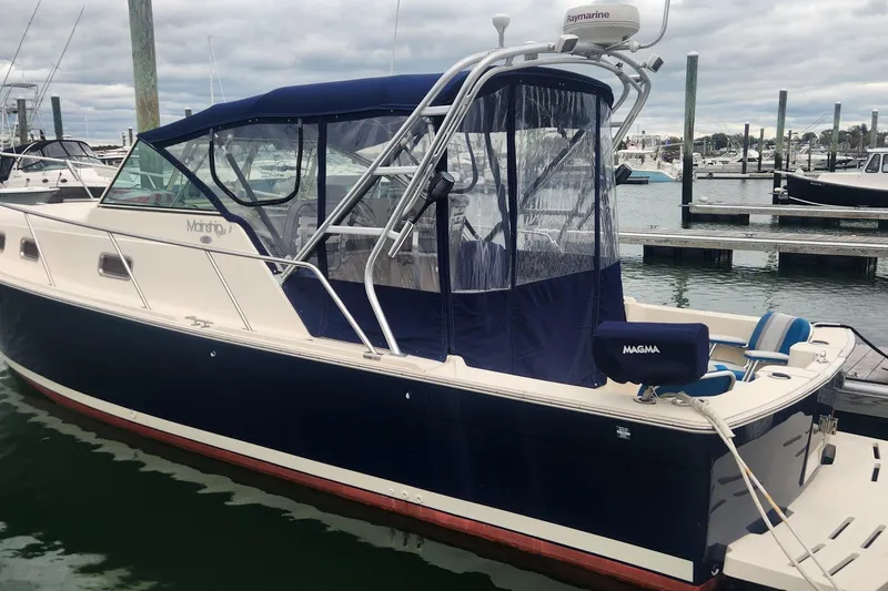 Slide: The Image of 2003 Mainship Pilot 30-II boat docked at marina, featuring blue canopy and white hull. - 3