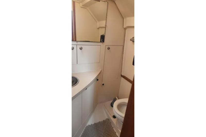 Slide: The Image of 2003 Mainship Pilot 30-II boat bathroom with sink, toilet, and storage cabinets. - 30