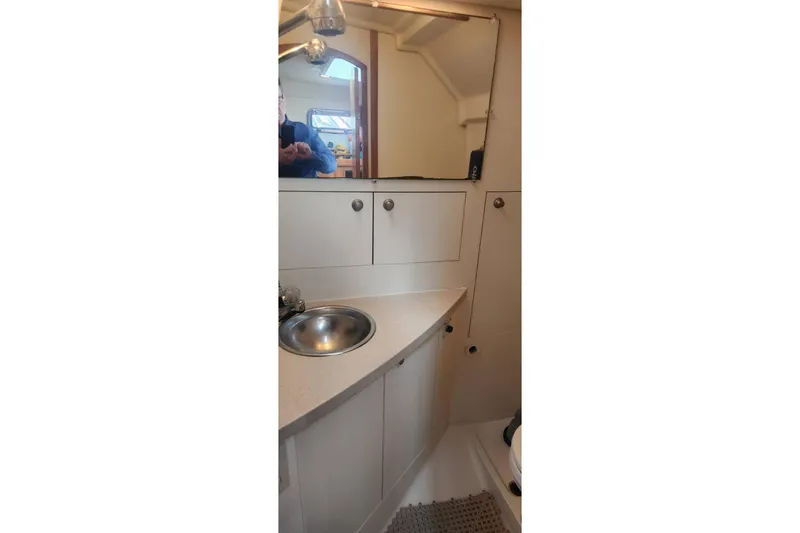 Slide: The Image of 2003 Mainship Pilot 30-II boat bathroom with sink, mirror, and storage cabinets. - 31