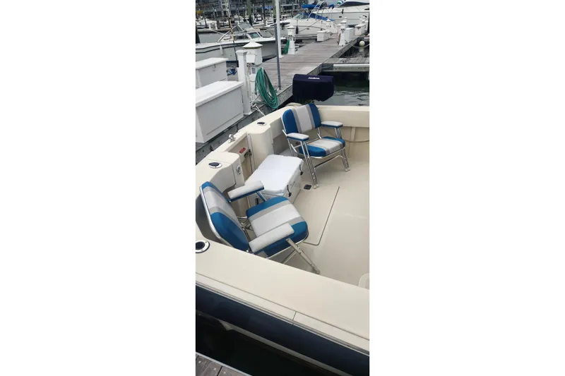 Slide: The Image of 2003 Mainship Pilot 30-II boat interior with blue and white seating at a marina. - 34