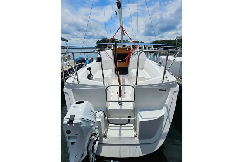 Slide: The Image of 1992 Hunter 27 sailboat with outboard motor, docked under a partly cloudy sky. - 21