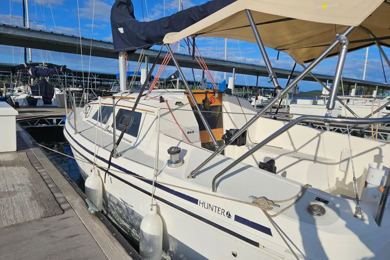 Slide: The Image of Hunter 27 sailboat from 1992 docked at a marina under a clear blue sky. - 5