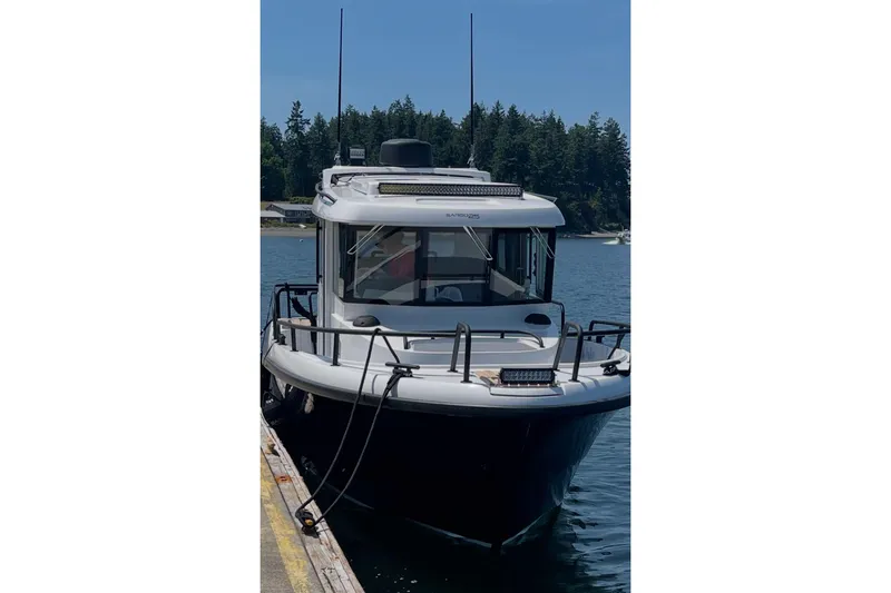 Slide: The Image of 2022 Sargo 25 boat docked on a sunny day with forested background. - 14