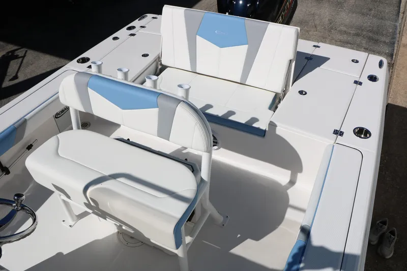 Slide: The Image of 2026 Robalo 226 Cayman boat interior with white and blue seating, cup holders, and storage compartments. - 27