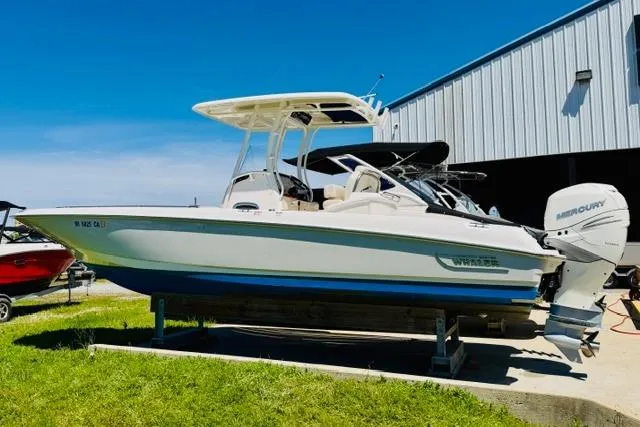 The Image of 2021 Boston Whaler 270 Dauntless boat with Mercury engine, parked near a metal building. - 1