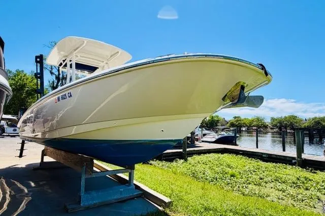 Slide: The Image of 2021 Boston Whaler 270 Dauntless boat on a stand by the water under a clear blue sky. - 5