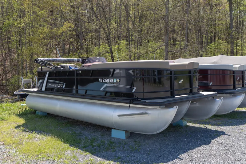 The Image of 2025 Starcraft EXS 3 pontoon boat parked on grassy area, surrounded by trees. - 0
