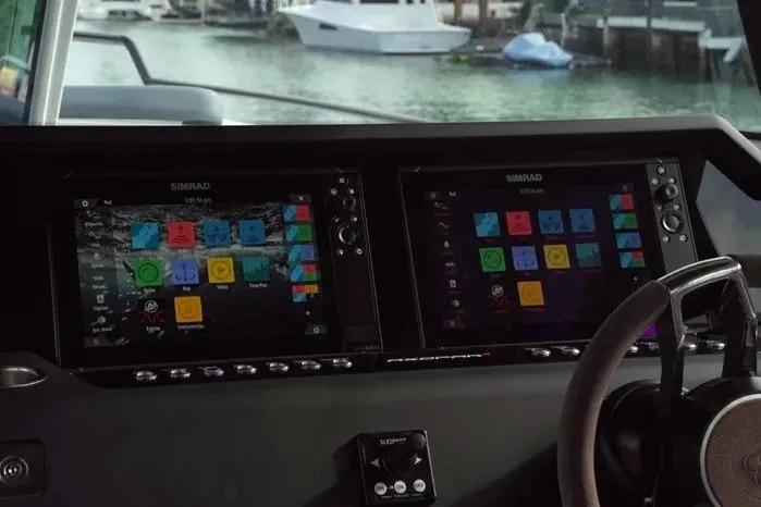 Slide: The Image of 2023 Axopar 37 XC Cross Cabin dashboard with dual Simrad displays, docked by the water. - 10