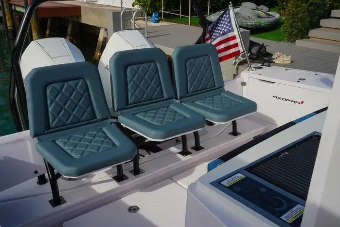 Slide: The Image of 2023 Axopar 37 XC Cross Cabin boat with blue seating and American flag. - 14