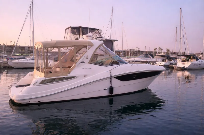 The Image of 2014 Sea Ray 330 Express Cruiser docked in a serene marina at sunset. - 0