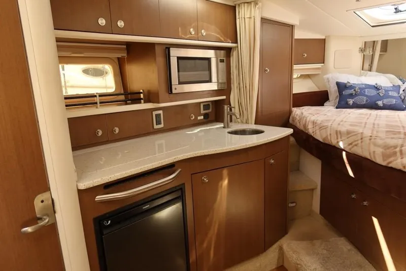 Slide: The Image of 2014 Sea Ray 330 Express Cruiser interior with kitchenette and cozy sleeping area. - 13