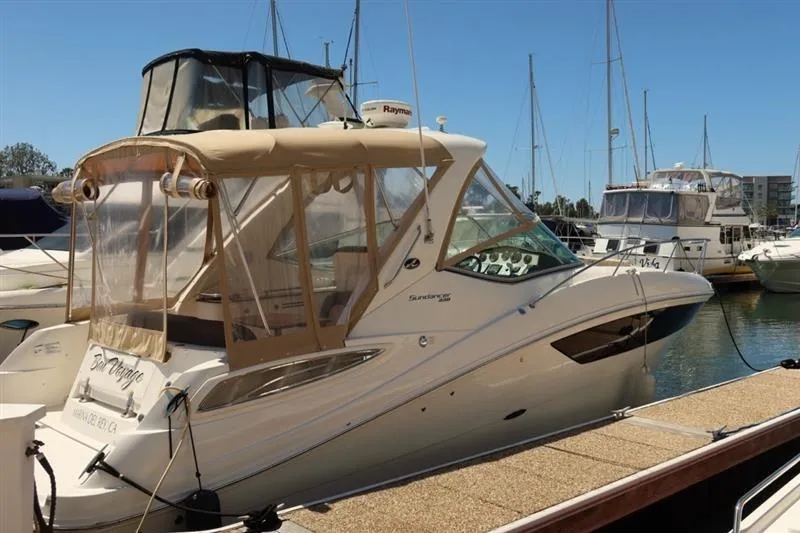 Slide: The Image of 2014 Sea Ray 330 Express Cruiser docked at marina, featuring tan canopy and sleek design. - 2