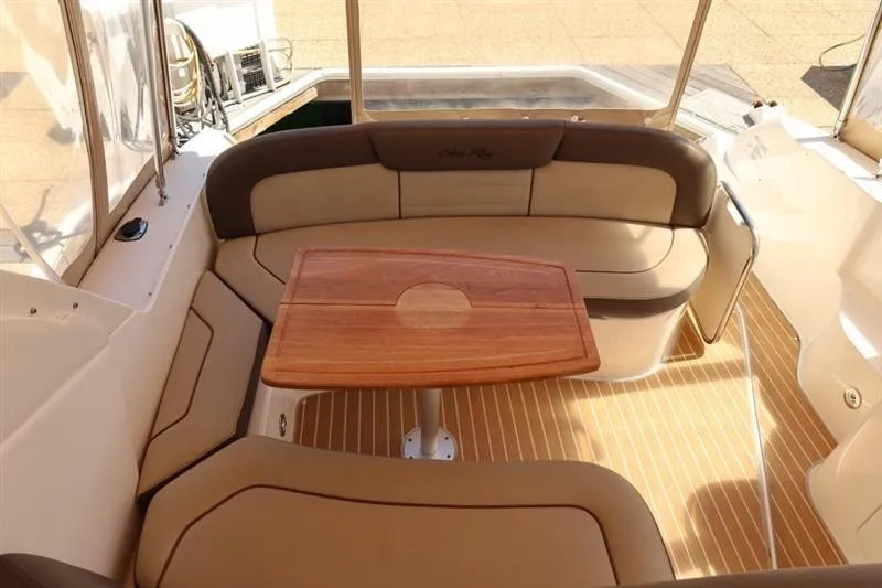 Slide: The Image of 2014 Sea Ray 330 Express Cruiser interior with cushioned seating and wooden table. - 8