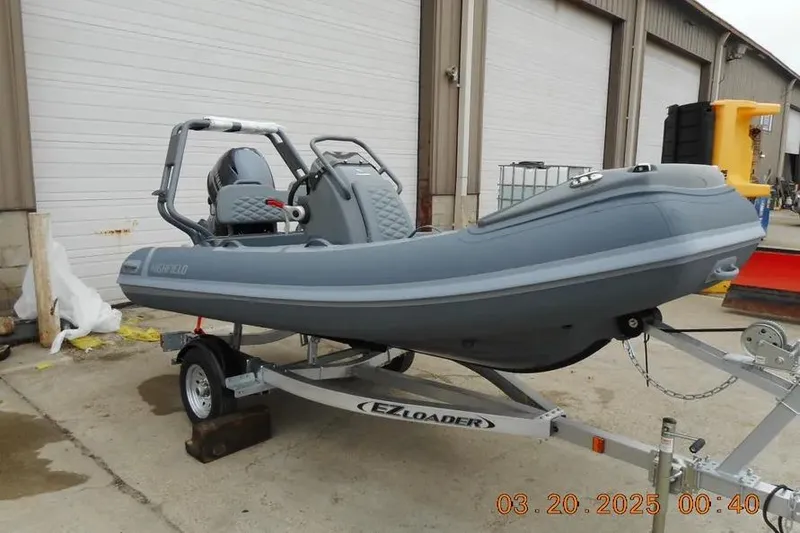 The Image of 2025 Highfield Sport 390 boat on EZ Loader trailer, parked outside a warehouse. - 3