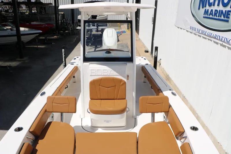 Slide: The Image of 2026 Robalo 246 Cayman boat with tan seating and sleek design in a marina setting. - 23