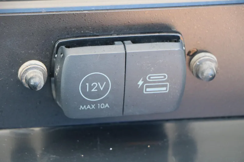 Slide: The Image of 12V power outlet on 2026 Robalo 246 Cayman boat dashboard. - 34