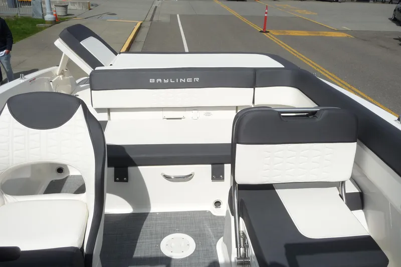 Slide: The Image of 2021 Bayliner VR5 Bowrider I/O interior with white and black seating, docked on pavement. - 9