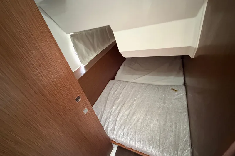 Slide: The Image of 2022 Jeanneau NC Weekender 1095 Fly cabin interior with wooden finish and cozy bedding. - 17