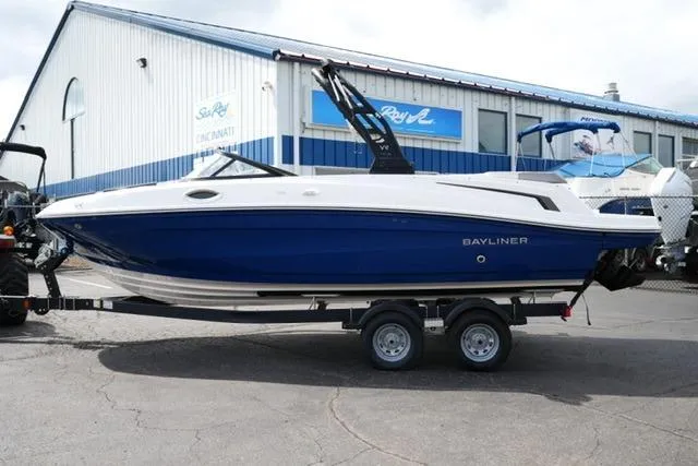 The Image of 2026 Bayliner VR6 Bowrider I/O boat on trailer, parked outside a marine dealership. - 2