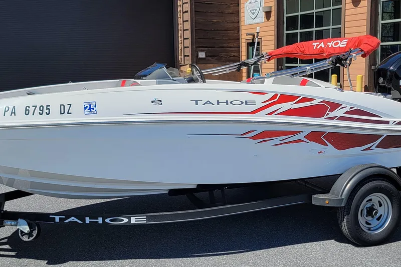 The Image of 2021 Tahoe T16 boat with red accents on a trailer, parked outdoors. - 0