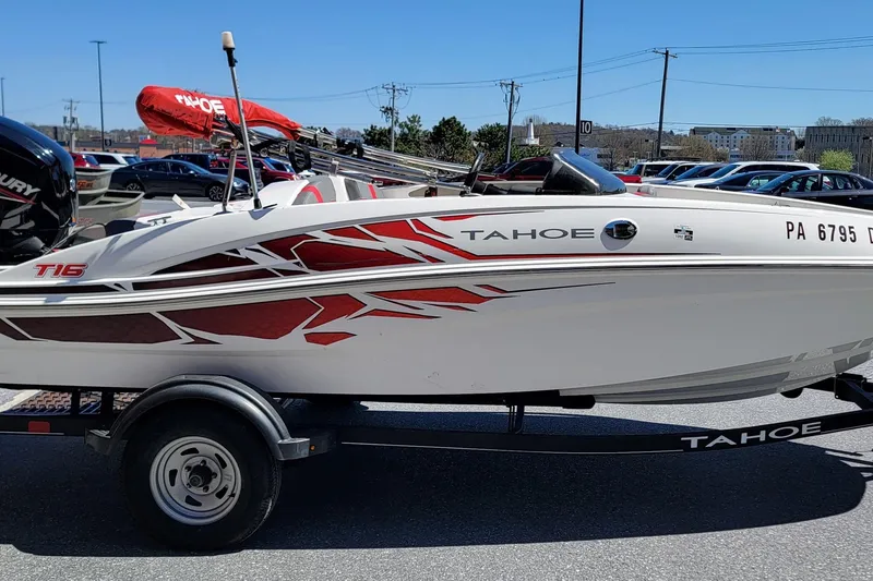 Slide: The Image of 2021 Tahoe T16 boat with red graphics on a trailer in a parking lot. - 3