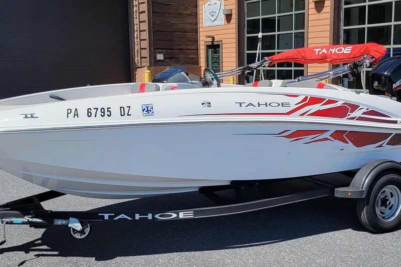 Slide: The Image of 2021 Tahoe T16 boat with red graphics on a trailer, parked outside a building. - 4